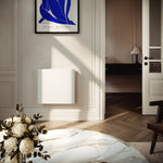 Radiateur Molia 1000W blanc fixé au mur près d'une porte, au-dessus d'un parquet en chevrons